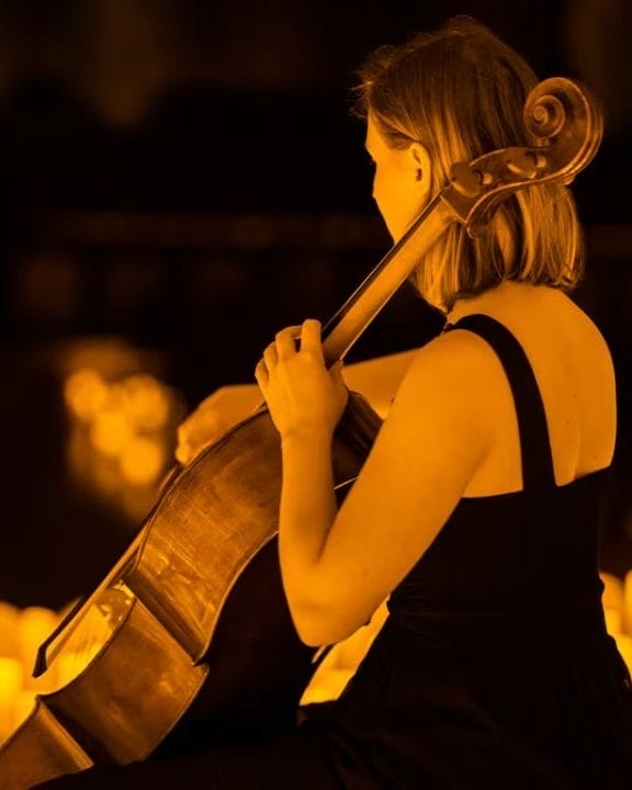 A woman playing the cello at a candlelight concert